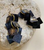 Pendientes negros de macramé y cuentas metálicas sobre fondo blanco.