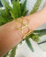 Brazalete rígido artesanal con círculos vacíos en latón dorado o plateado.