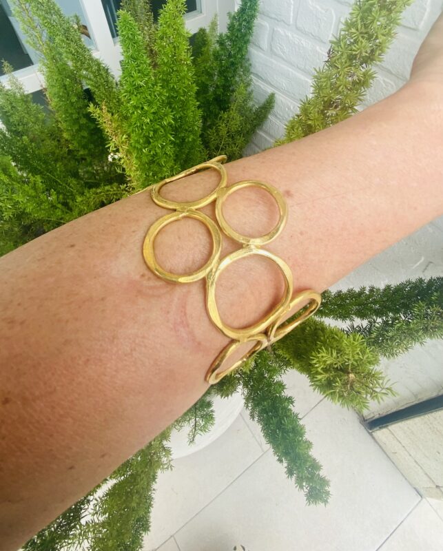 Brazalete rígido artesanal con círculos vacíos en latón dorado o plateado.