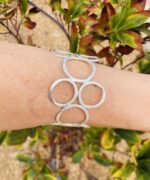 Brazalete rígido artesanal con círculos vacíos en latón dorado o plateado.