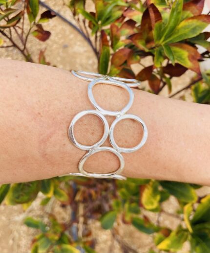 Brazalete rígido artesanal con círculos vacíos en latón dorado o plateado.