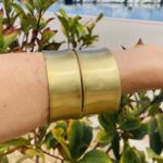 Brazalete rígido doble en latón dorado, ajustable y artesanal, estilo boho chic.