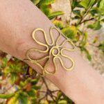 Brazalete artesanal de latón en forma de flor, ajustable y boho chic.