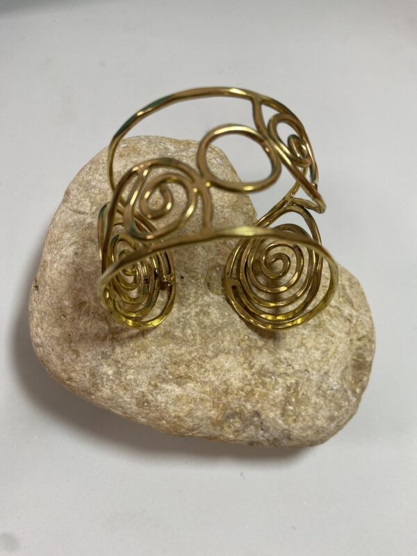 Brazalete artesanal en latón con espirales y círculos, boho chic y étnico.