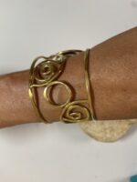 Brazalete artesanal en latón con espirales y círculos, boho chic y étnico.