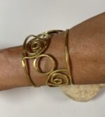 Brazalete artesanal en latón con espirales y círculos, boho chic y étnico.