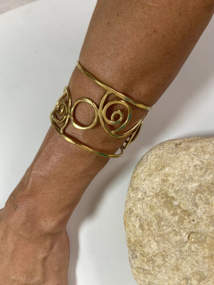 Brazalete artesanal en latón con espirales y círculos, boho chic y étnico.