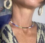 Mujer con collar rígido de latón dorado y perlas multicolor, hecho a mano en India, estilo boho chic.