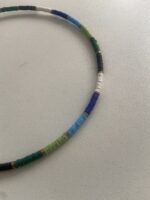 Detalle del collar artesanal de latón dorado con perlas multicolor, hecho a mano en India.