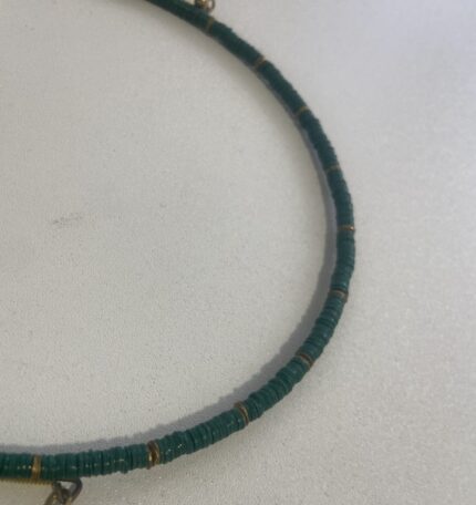 Detalle del collar artesanal de latón dorado con perlas verde, hecho a mano en India.