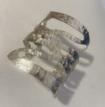 Lateral del brazalete abierto con formas onduladas, hecho a mano en India.