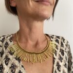 Collar artesanal dorado con diseño de rayos de sol y detalle de macramé burdeos, hecho a mano en India.