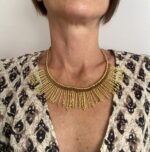 Collar artesanal dorado con diseño de rayos de sol y detalle de macramé burdeos, hecho a mano en India.