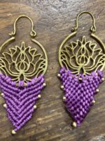 Pendientes de latón y macramé lila claro con diseño artesanal, sobre mesa.