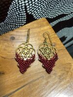Pendientes de latón y macramé rojo, diseño artesanal indio, sobre mesa.