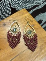 Pendientes de latón con macramé marrón, diseño artesanal, sobre mesa.