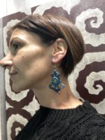 Pendientes de macramé azul oscuro con piedra central, usados por modelo.