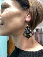 Pendientes de macramé negros con piedra central ovalada, llevados por modelo.