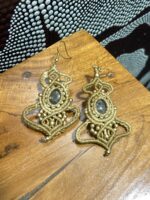 Pendientes de macramé beige con piedra central y cuentas doradas, artesanales de India, sobre mesa