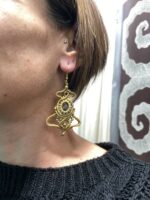Pendientes de macramé beige con piedra central ovalada, llevados por modelo.