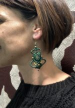 Pendientes de macramé verdes con piedra central y cuentas doradas, artesanales de India, llevados por una modelo.