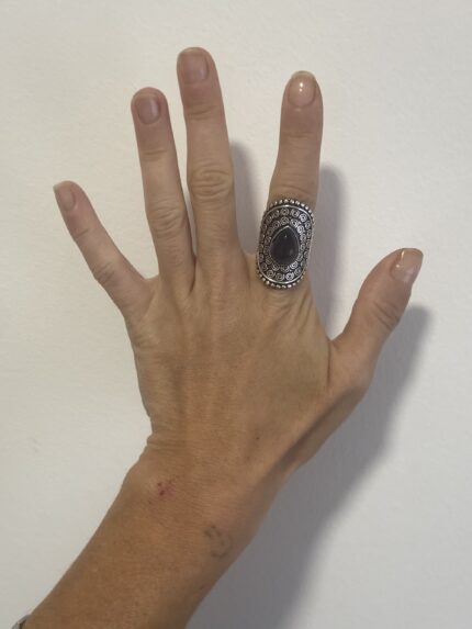 mano abierta mostrando anillo étnico grande en plata con piedra violeta