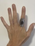 mano abierta mostrando anillo étnico grande en plata con piedra violeta
