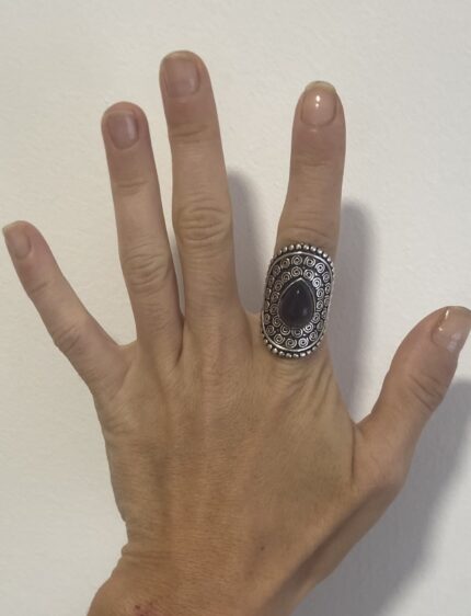 mano abierta mostrando anillo étnico grande en plata con piedra violeta