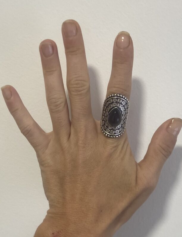 mano abierta mostrando anillo étnico grande en plata con piedra violeta
