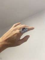 anillo bohemio violeta en mano relajada sobre fondo neutro