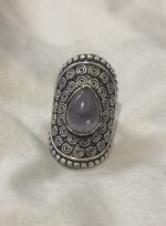 anillo étnico grande en baño de plata con piedra violeta apoyado en superficie