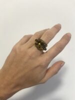 Anillo de latón con siete piedras Ojo de Tigre ajustable visto a distancia en la mano.