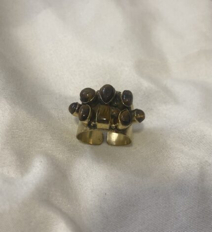 Anillo de latón con siete piedras Ojo de Tigre fotografiado desde arriba sobre una superficie neutra.