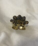 Anillo de latón con siete piedras Ojo de Tigre fotografiado desde arriba sobre una superficie neutra.