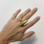 anillo de latón dorado ajustable visto en la mano a distancia