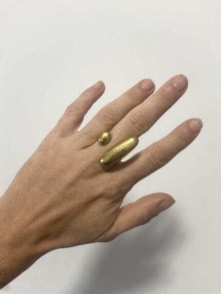 anillo de latón dorado ajustable visto en la mano a distancia