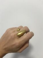 mano llevando anillo abierto en latón dorado envejecido con formas alargadas