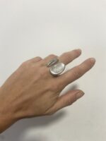 anillo abierto de latón plata colocado de lado sobre tela blanca