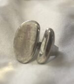 mano llevando anillo abierto en latón color plata con dos formas orgánicas