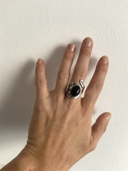 anillo con piedra negra visto en la mano a distancia