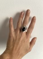 anillo con piedra negra visto en la mano a distancia