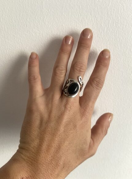 anillo con piedra negra visto en la mano a distancia
